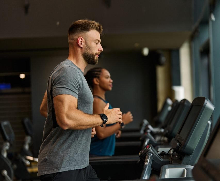 Portrait of a young man and a black woman exercising in a gym, running using  thereadmill machine equipment, healthy lifestyle and cardio exercise at fitness club concepts