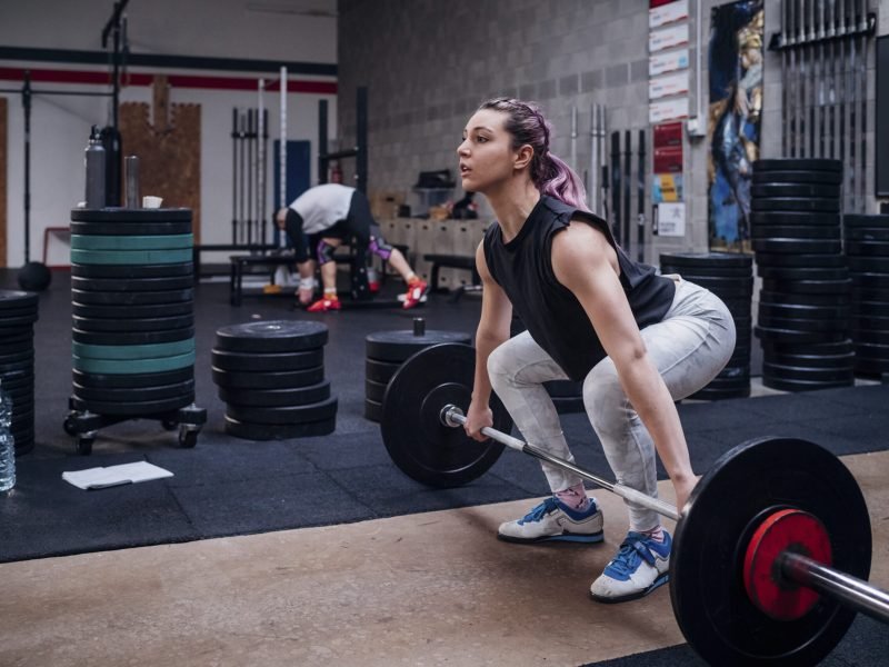 Young woman lifting barbell in gym